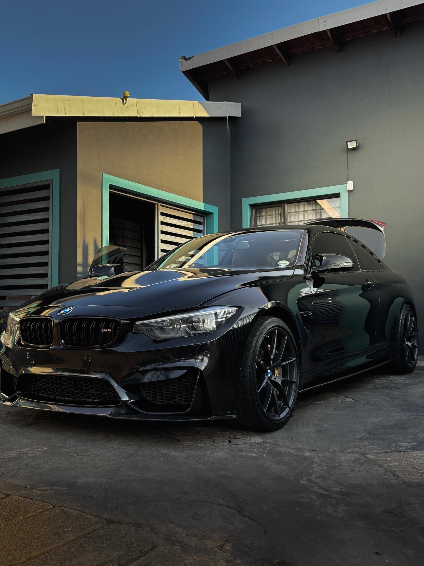 Sleek black BMW M4 with a mirror-like gloss finish parked outside a detailing studio